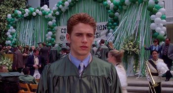 Movie still from “Spider-Man” (2002), directed by Sam Raimi – A young man in a graduation cap and gown; Medium shot, Over the shoulder angle