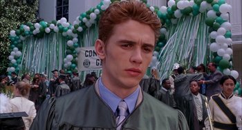Movie still from “Spider-Man” (2002), directed by Sam Raimi – A young man in a graduation gown and tie; Close Up shot, Low angle