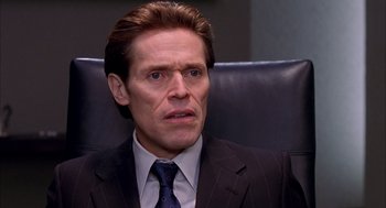 Movie still from “Spider-Man” (2002), directed by Sam Raimi – Willem dafoe in a suit and tie sitting in an office chair; Close Up shot, Over the shoulder angle