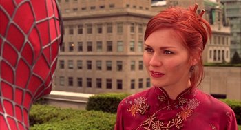 Movie still from “Spider-Man” (2002), directed by Sam Raimi – A woman with red hair standing in front of a building; Close Up shot, Over the shoulder angle