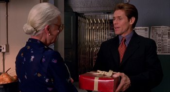 Movie still from “Spider-Man” (2002), directed by Sam Raimi – A man in a suit holding a red gift box; Close Up shot, Over the shoulder angle