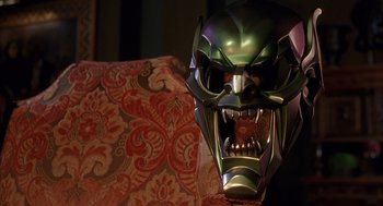 Movie still from “Spider-Man” (2002), directed by Sam Raimi – A green and purple mask with a face on it; Close Up shot, Low angle