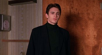 Movie still from “Spider-Man” (2002), directed by Sam Raimi – A young man in a black jacket and a green sweater; Medium shot, High angle