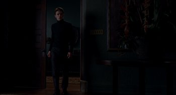 Movie still from “Spider-Man” (2002), directed by Sam Raimi – A man standing in front of a painting in a dark room; Wide shot, Low angle