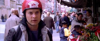 Movie still from “Spider-Man 2” (2004), directed by Sam Raimi – A man wearing a red helmet standing on the sidewalk; Close Up shot, Over the shoulder angle