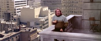 Movie still from “Spider-Man 2” (2004), directed by Sam Raimi – A man standing on top of a building eating a sandwich; Wide shot, Overhead angle