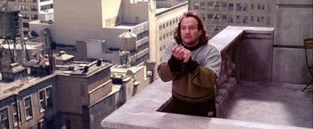 Movie still from “Spider-Man 2” (2004), directed by Sam Raimi – A man standing on top of a building looking at the camera; Medium shot, Low angle