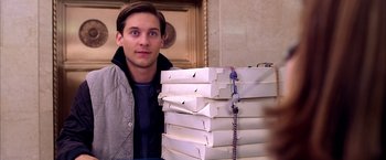 Movie still from “Spider-Man 2” (2004), directed by Sam Raimi – A man standing in front of a stack of pizza boxes; Medium shot, Over the shoulder angle