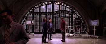 Movie still from “Spider-Man 2” (2004), directed by Sam Raimi – A group of men standing in front of a building; Wide shot, Over the shoulder angle