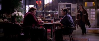 Movie still from “Spider-Man 2” (2004), directed by Sam Raimi – Two people sitting at a table in a restaurant; Medium shot, Over the shoulder angle