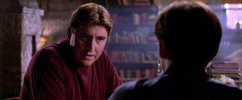Movie still from “Spider-Man 2” (2004), directed by Sam Raimi – A man sitting in front of another man in front of bookshelves; Close Up shot, Over the shoulder angle