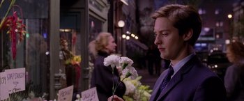 Movie still from “Spider-Man 2” (2004), directed by Sam Raimi – A man in a suit holding a flower in his hand; Close Up shot, Over the shoulder angle