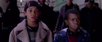 Movie still from “Spider-Man 2” (2004), directed by Sam Raimi – Two young boys are standing in front of a group of people; Close Up shot, Low angle