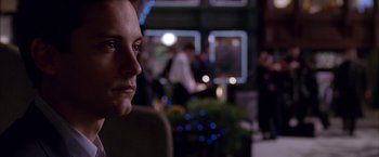 Movie still from “Spider-Man 2” (2004), directed by Sam Raimi – A person's face at a party; Close Up shot, Over the shoulder angle