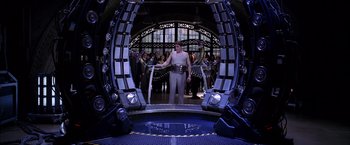 Movie still from “Spider-Man 2” (2004), directed by Sam Raimi – A man standing in front of a group of people in a room; Wide shot, Low angle