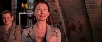 Movie still from “Spider-Man 2” (2004), directed by Sam Raimi – A woman in a gray jacket is smiling for the camera; Close Up shot, Low angle