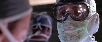 Movie still from “Spider-Man 2” (2004), directed by Sam Raimi – A man wearing a surgical mask and goggles in front of another man wearing a surgical mask and googles; Close Up shot, Low angle