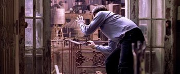 Movie still from “Spider-Man 2” (2004), directed by Sam Raimi – A man standing on top of an iron railing; Wide shot, Overhead angle