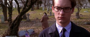 Movie still from “Spider-Man 2” (2004), directed by Sam Raimi – A man wearing glasses standing in front of a cemetery; Close Up shot, Low angle