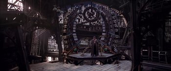 Movie still from “Spider-Man 2” (2004), directed by Sam Raimi – A man standing in front of a large metal structure; Wide shot, High angle