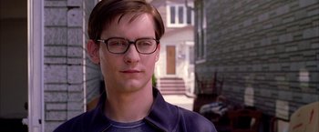 Movie still from “Spider-Man 2” (2004), directed by Sam Raimi – A young man wearing glasses standing in front of a house; Close Up shot, Over the shoulder angle