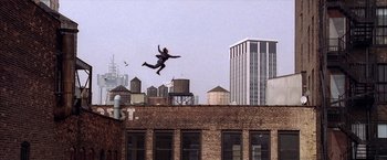 Movie still from “Spider-Man 2” (2004), directed by Sam Raimi – A man jumping in the air on top of a building; Extreme Wide shot, Overhead angle