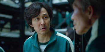 Movie still from “Squid Game” (2021), created by Hwang Dong-hyuk – A man in a green jacket is looking at another man in a green jacket; Close Up shot, Over the shoulder angle