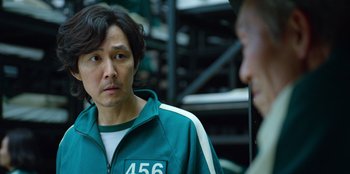 Movie still from “Squid Game” (2021), created by Hwang Dong-hyuk – A man in a green jacket is talking to another man in a green jacket; Close Up shot, Over the shoulder angle