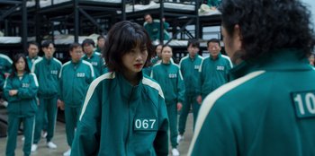 Movie still from “Squid Game” (2021), created by Hwang Dong-hyuk – A group of people standing in a room; Medium shot, Over the shoulder angle