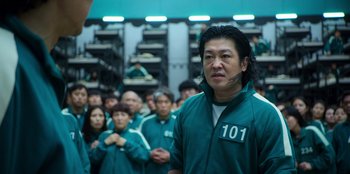 Movie still from “Squid Game” (2021), created by Hwang Dong-hyuk – A group of people standing in front of a building; Medium shot, High angle
