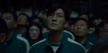 Movie still from “Squid Game” (2021), created by Hwang Dong-hyuk – A group of people standing in front of a wall; Close Up shot, Low angle