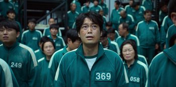 Movie still from “Squid Game” (2021), created by Hwang Dong-hyuk – A group of people wearing green and white uniforms; Close Up shot, Low angle
