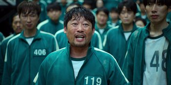 Movie still from “Squid Game” (2021), created by Hwang Dong-hyuk – A group of men in green uniforms standing next to each other; Close Up shot, Low angle