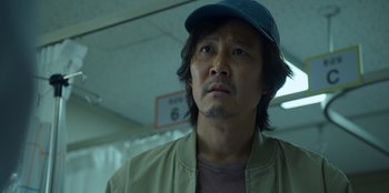 Movie still from “Squid Game” (2021), created by Hwang Dong-hyuk – A person wearing a hat; Close Up shot, Low angle