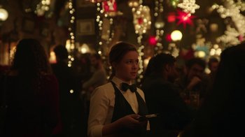 Movie still from “Mr. Robot” (2015), created by Sam Esmail – A woman holding a cell phone standing in front of a crowd; Medium shot, Over the shoulder angle