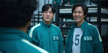 Movie still from “Squid Game” (2021), created by Hwang Dong-hyuk – A couple of men standing next to each other in a room; Close Up shot, Over the shoulder angle