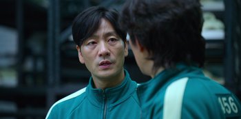 Movie still from “Squid Game” (2021), created by Hwang Dong-hyuk – A man wearing a green jacket talking to another man; Close Up shot, Over the shoulder angle