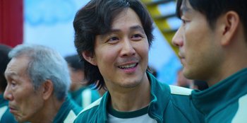 Movie still from “Squid Game” (2021), created by Hwang Dong-hyuk – A person wearing a green jacket; Close Up shot, Over the shoulder angle
