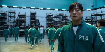 Movie still from “Squid Game” (2021), created by Hwang Dong-hyuk – A group of people in green suits in a room; Medium shot, Low angle