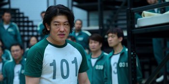 Movie still from “Squid Game” (2021), created by Hwang Dong-hyuk – A group of men standing next to each other; Medium shot, Over the shoulder angle