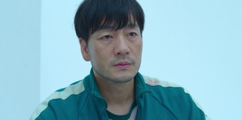 Movie still from “Squid Game” (2021), created by Hwang Dong-hyuk – A person wearing a green jacket; Close Up shot, High angle
