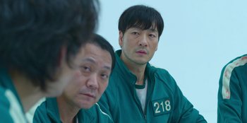 Movie still from “Squid Game” (2021), created by Hwang Dong-hyuk – Two men in green jackets looking at the camera; Close Up shot, Over the shoulder angle