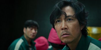 Movie still from “Squid Game” (2021), created by Hwang Dong-hyuk – A person wearing a green shirt; Close Up shot, Over the shoulder angle