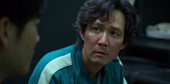Movie still from “Squid Game” (2021), created by Hwang Dong-hyuk – A person wearing a green jacket; Close Up shot, Over the shoulder angle