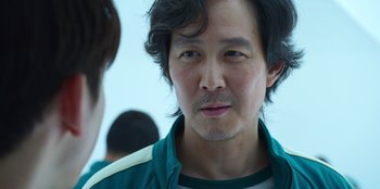 Movie still from “Squid Game” (2021), created by Hwang Dong-hyuk – A person wearing a green jacket; Close Up shot, Over the shoulder angle