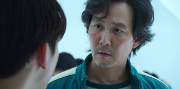 Movie still from “Squid Game” (2021), created by Hwang Dong-hyuk – A person talking to another person; Close Up shot, Over the shoulder angle