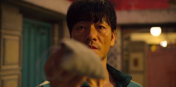 Movie still from “Squid Game” (2021), created by Hwang Dong-hyuk – A person holding something in his hand; Close Up shot, High angle