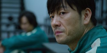 Movie still from “Squid Game” (2021), created by Hwang Dong-hyuk – A person looking at the camera; Close Up shot, Low angle