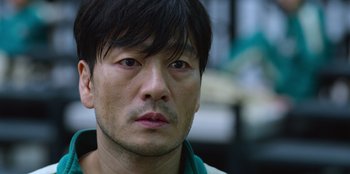 Movie still from “Squid Game” (2021), created by Hwang Dong-hyuk – A person wearing a green shirt; Close Up shot, Over the shoulder angle