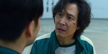 Movie still from “Squid Game” (2021), created by Hwang Dong-hyuk – A man in a green jacket talking to another man in a green jacket; Close Up shot, Over the shoulder angle